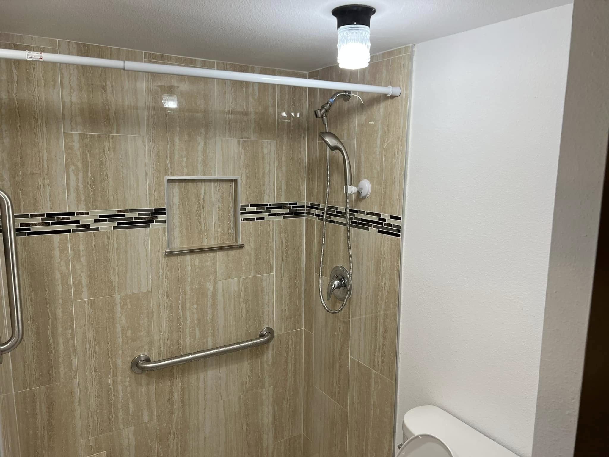 Shower with tile walls, mosaic trim and a recessed niche